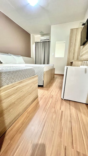 A hotel room with a bed, a desk, and a refrigerator.