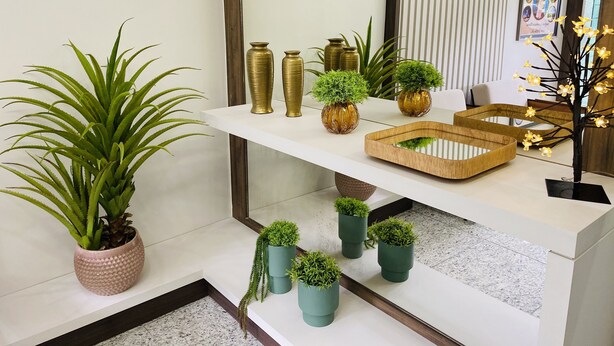 Un interior moderno con una consola blanca que exhibe diversos objetos decorativos, entre ellos macetas y jarrones.