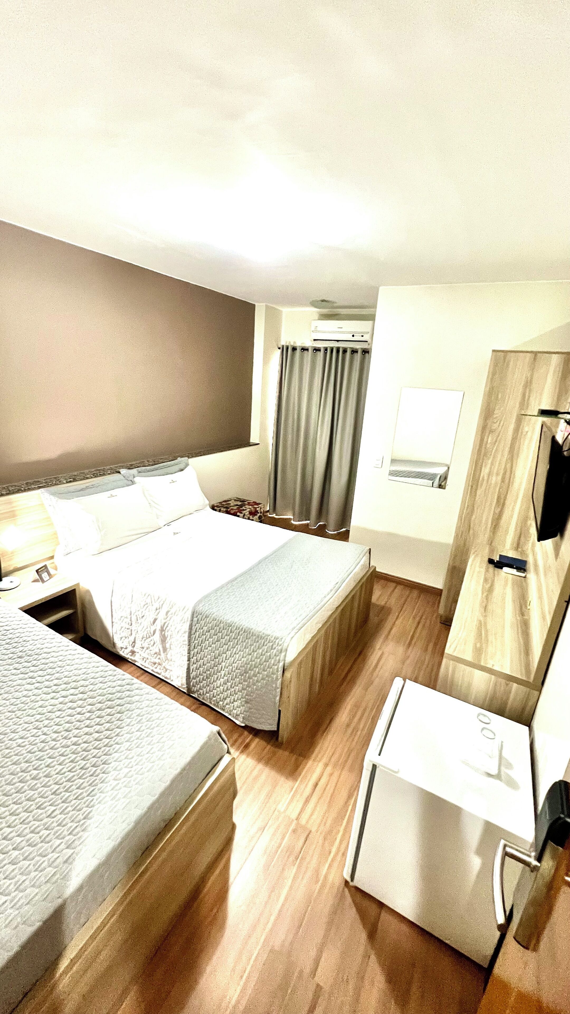 Una habitación de hotel con cama, escritorio, silla, televisor y un mueble pequeño.