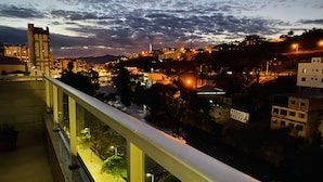 Panorama nocturno de una ciudad con edificios, un río y un puente.