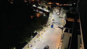 Vista aérea noturna de uma rua urbana com edifícios, veículos e pedestres.