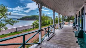 A wooden porch with a view of the beach and ocean. - Evangeline's Tower Bed & Breakfast (Parrsboro)