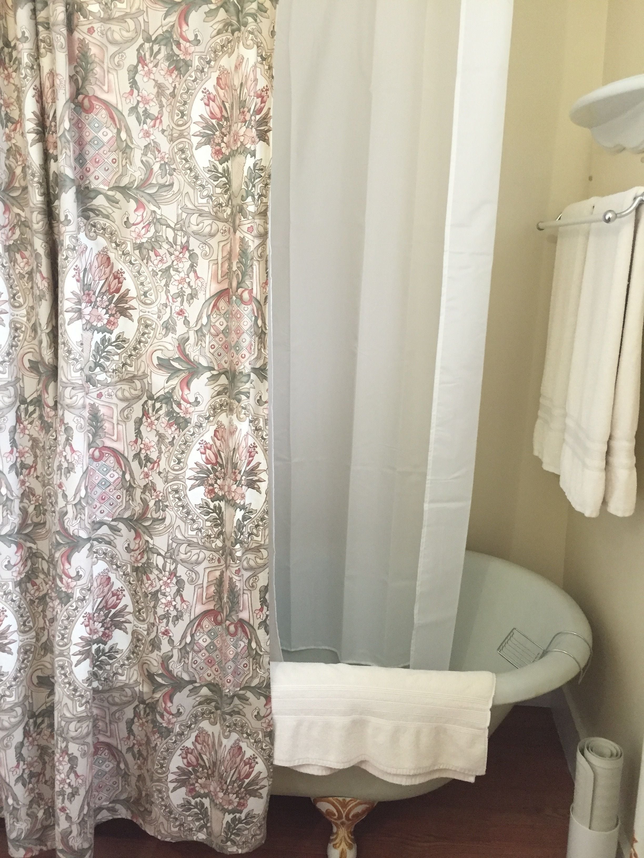 Une salle de bain avec un rideau de douche, une baignoire et un porte-serviettes.