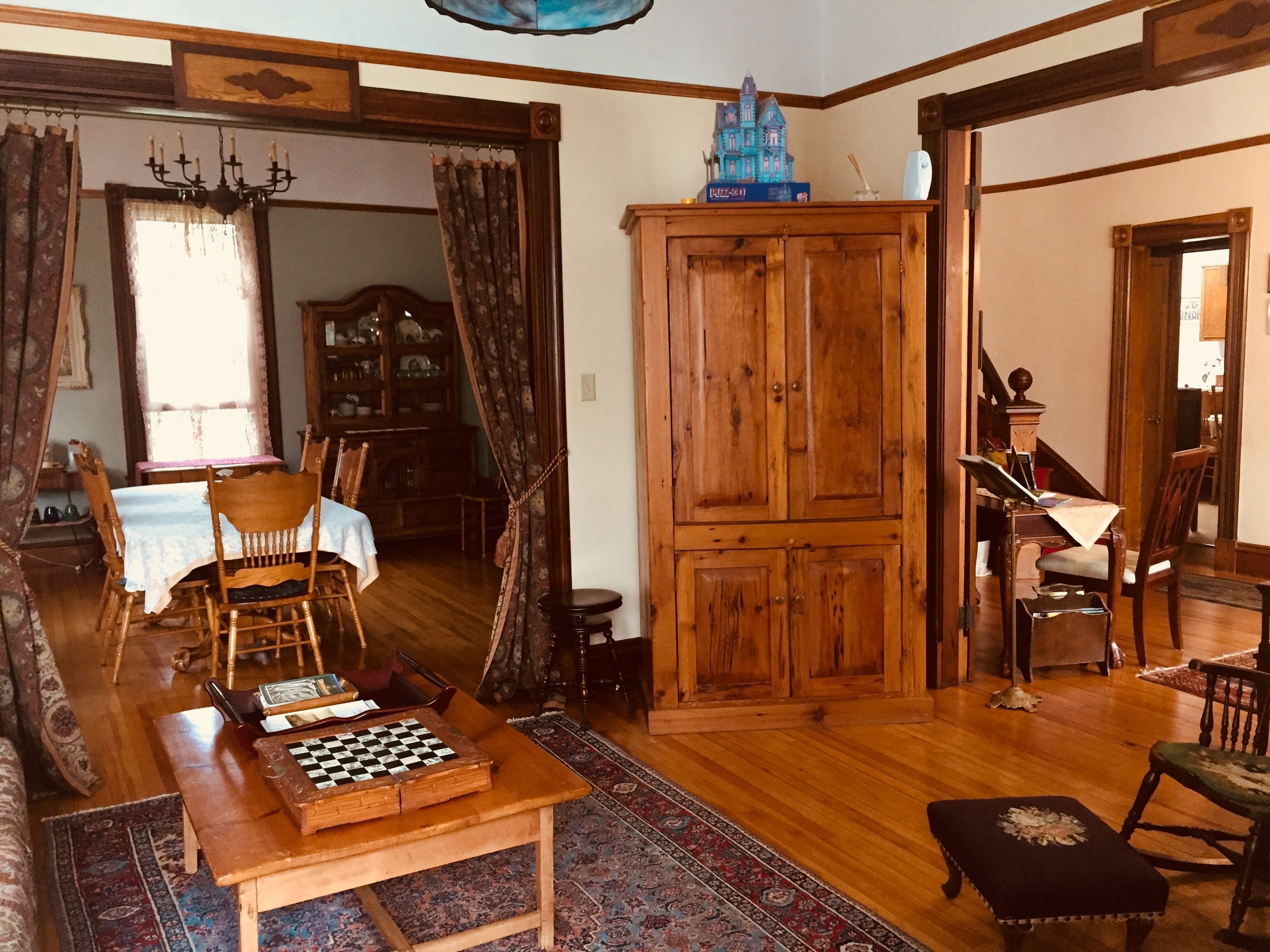 A traditional living room with a wooden table, chessboard, and a large wooden cabinet.