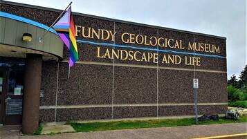 The exterior of the Fundy Geological Museum, featuring a prominent sign with the museum's name and a colorful flag.