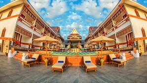 Ein symmetrisches Hotel mit einem zentral gelegenen Pool, mehreren Lounges und einer markanten, dreieckigen Dachkonstruktion.
