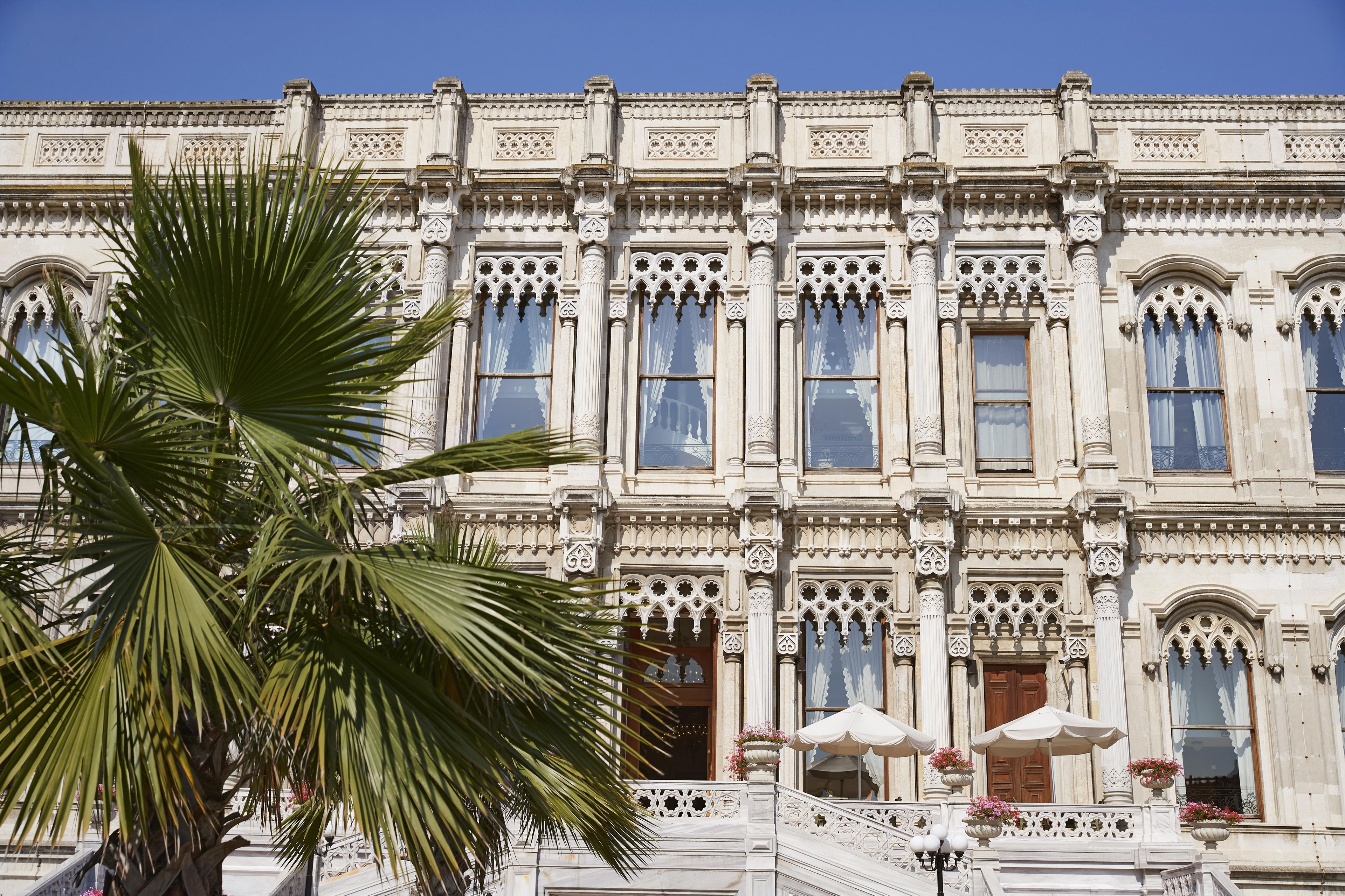 A historic building with ornate architectural details, large windows, and a palm tree in the foreground.