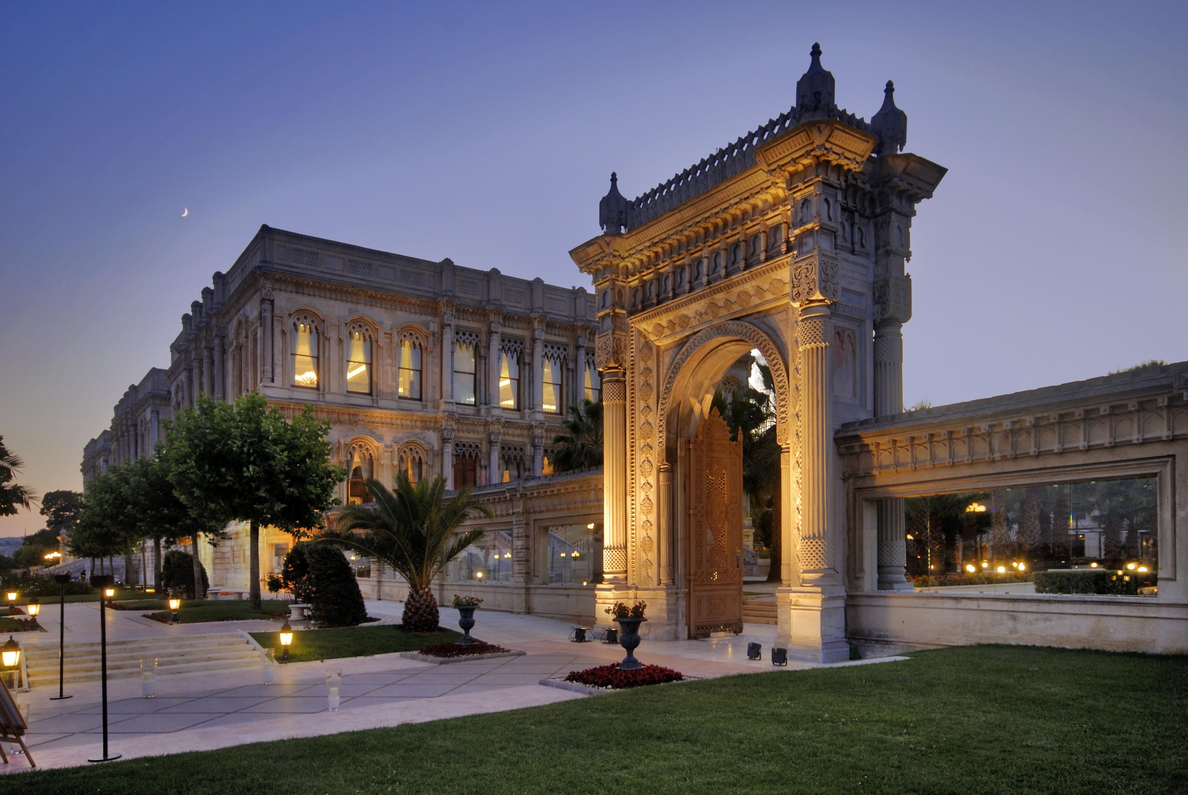 A grand building with an ornate entrance, large windows, and a well-maintained lawn.