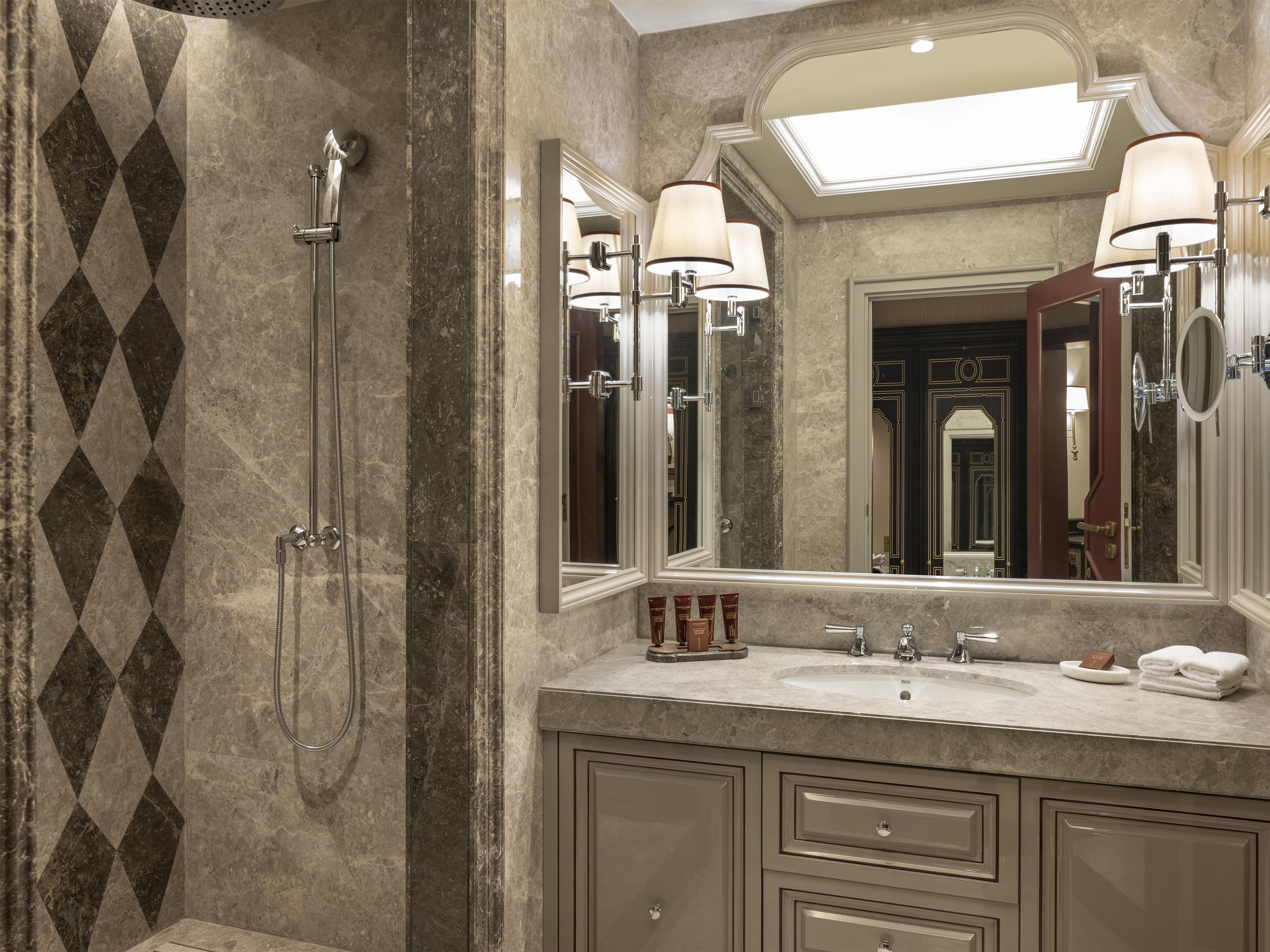 Een badkamer met een douche, een wastafel en een grote spiegel.