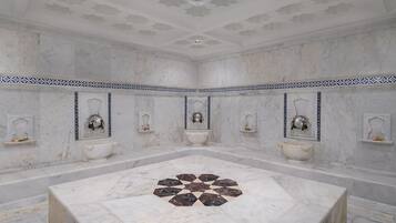 A large bathroom with a central marble sink, multiple smaller sinks, and a decorative floor pattern.