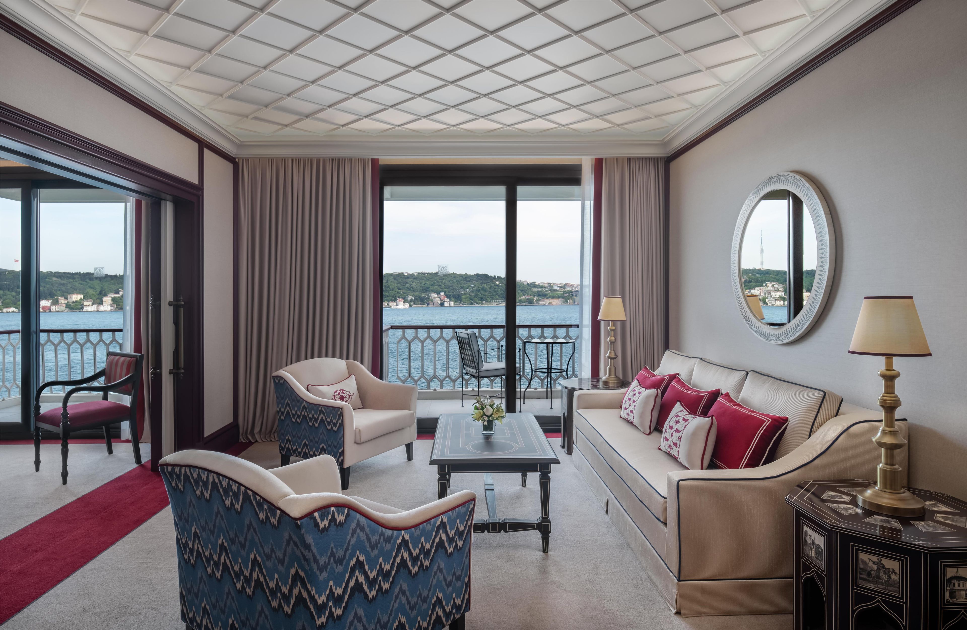 Ein Hotelzimmer mit Balkon, einer Couch, einem Sessel, einem Tisch und einer Lampe.