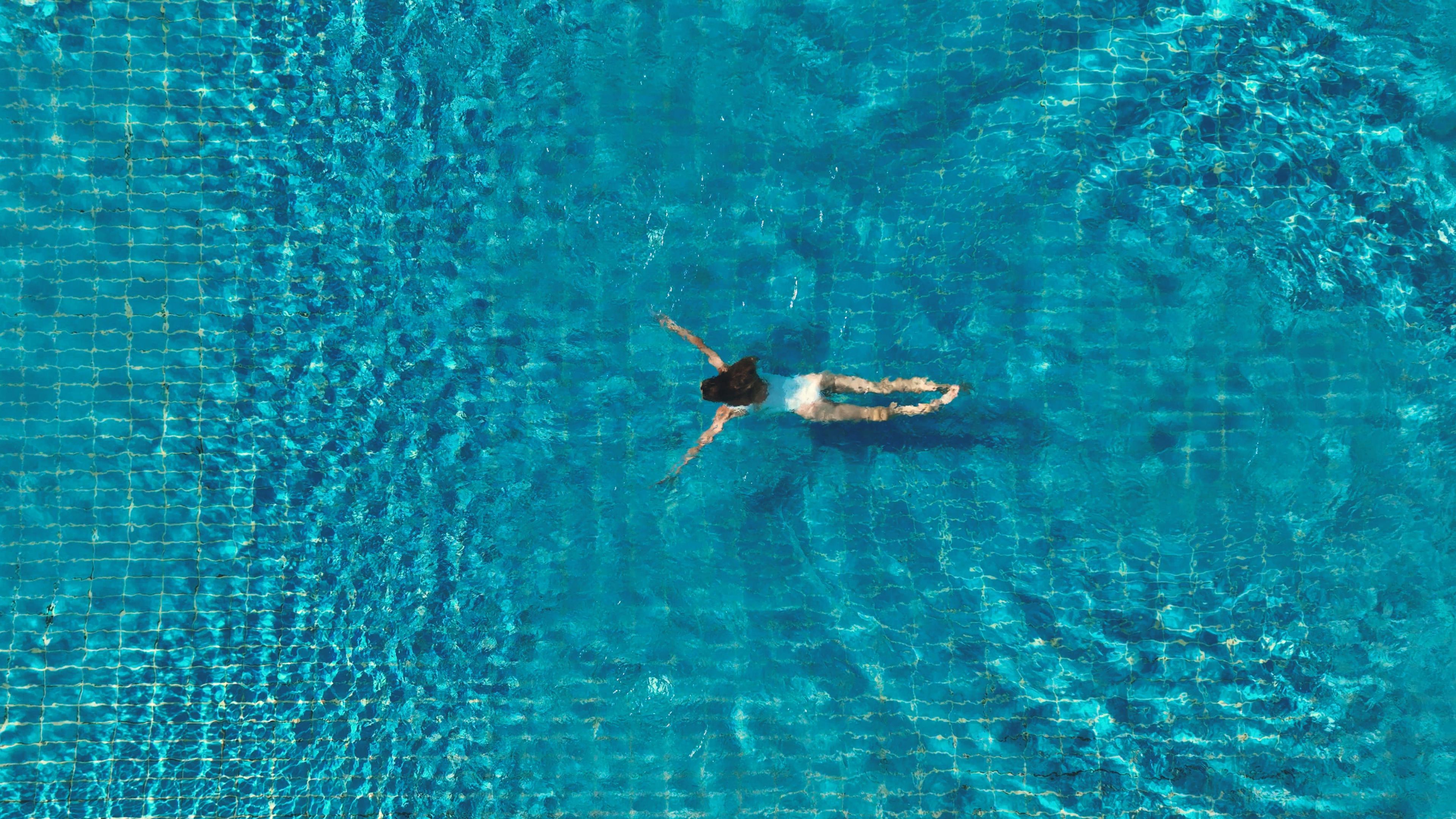 A person swimming in a clear blue pool.