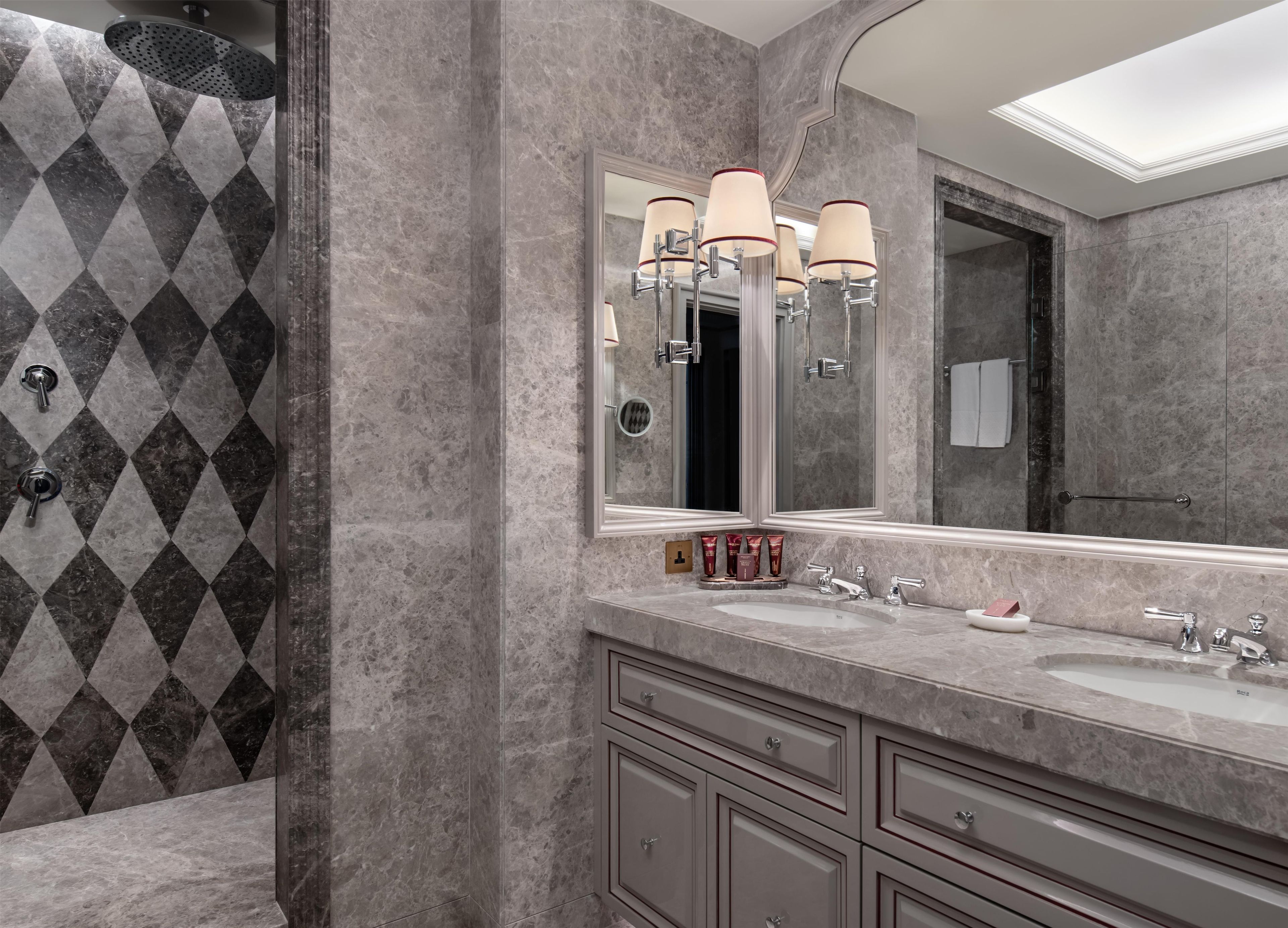 A modern bathroom with a large mirror, dual sinks, and a shower area.