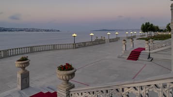 A waterfront promenade with a red carpet leading to a staircase, bordered by balustrades and street lamps.