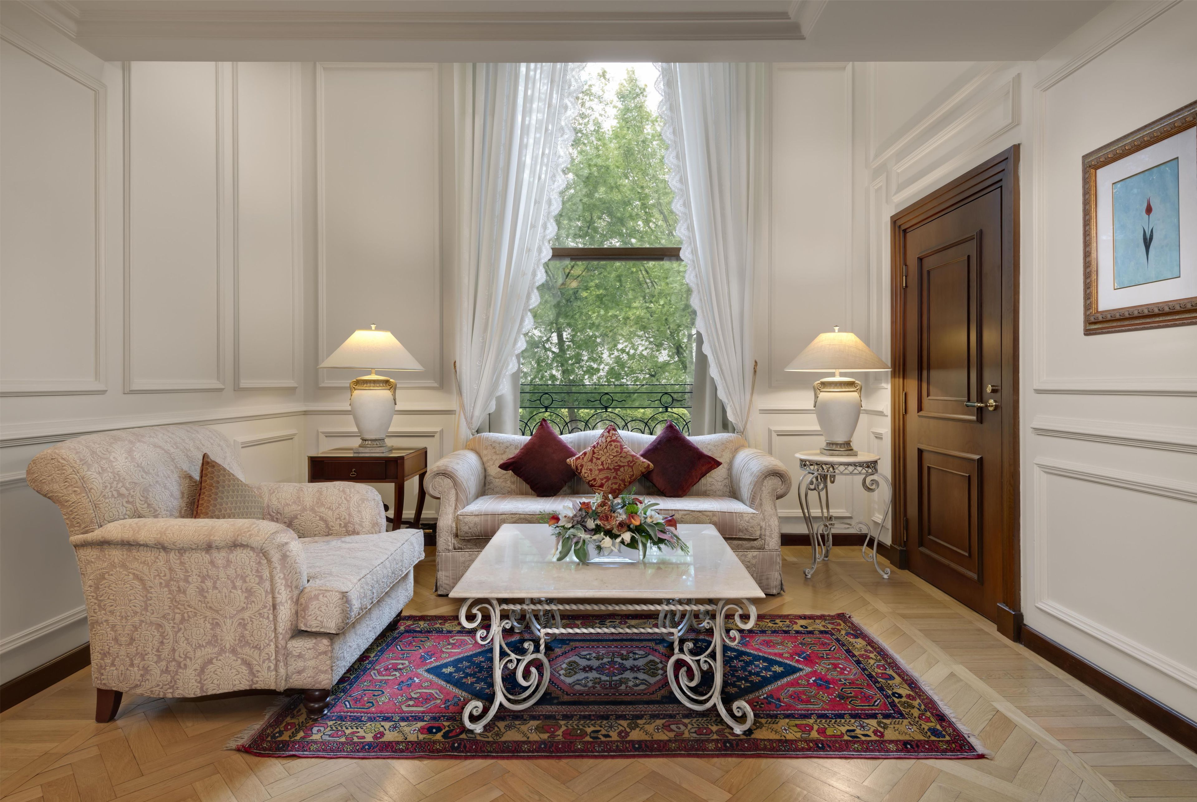 Een klassieke kamer met een bank, fauteuils, een salontafel en een kamerkleed met dessin.