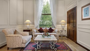 Een klassieke kamer met een bank, fauteuils, een salontafel en een kamerkleed met dessin.