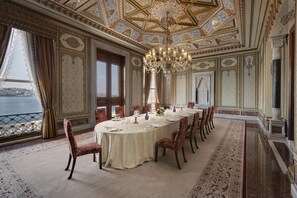 A formal dining room with a large round table, ornate chairs, and a chandelier. - Ciragan Palace Kempinski (Istanbul)