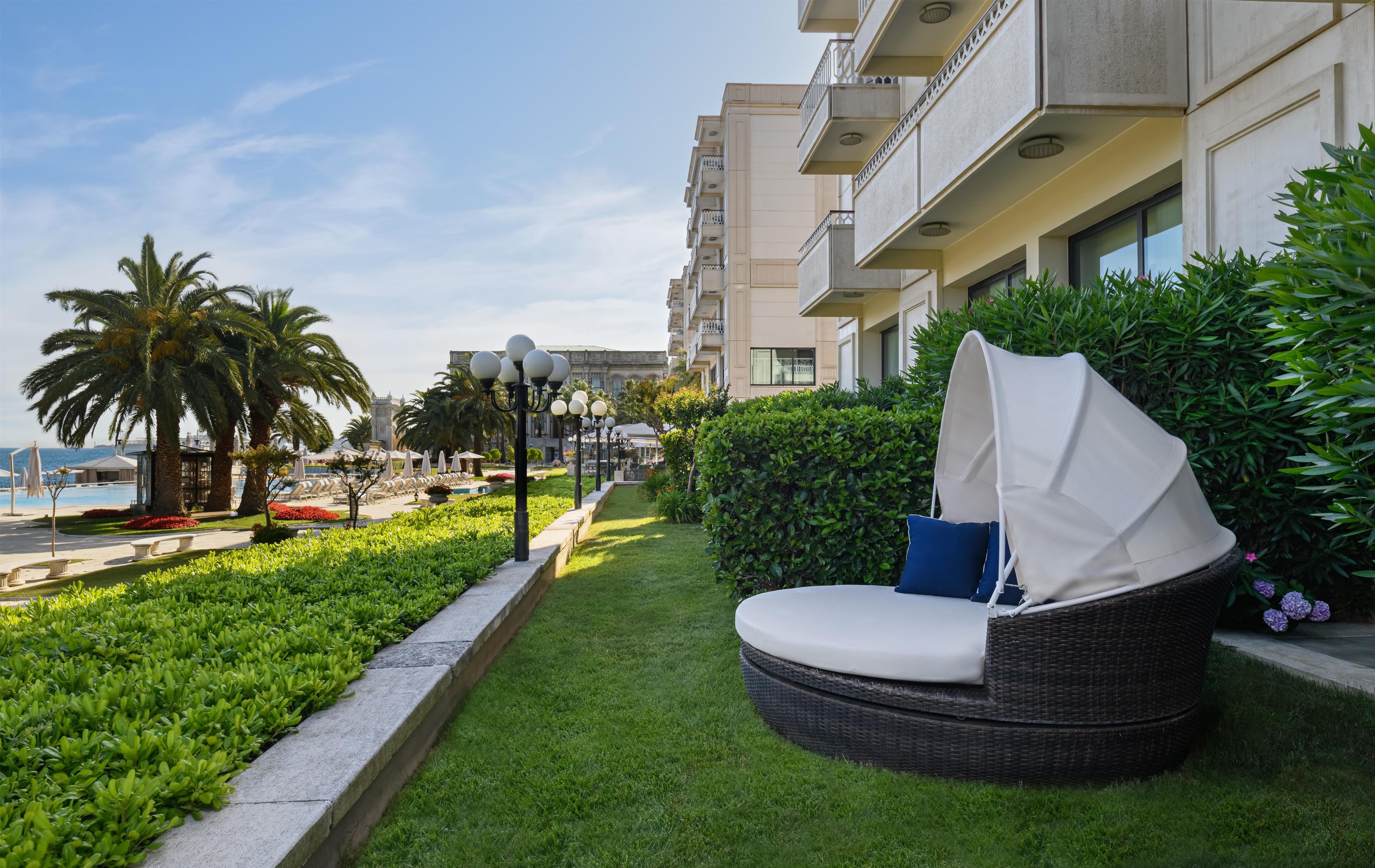 A hotel with a pool, outdoor seating, and lush greenery.