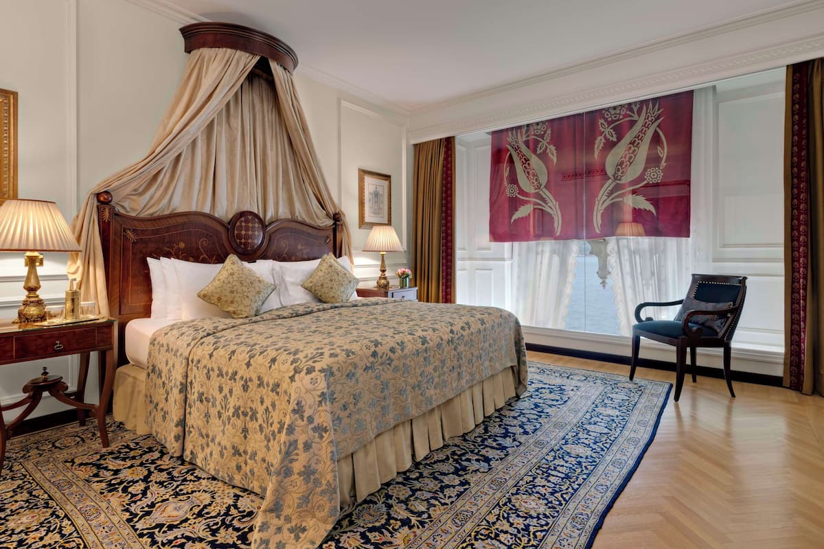 A four-poster canopy bed with a floral bedspread, a matching nightstand, and a large ornate rug.