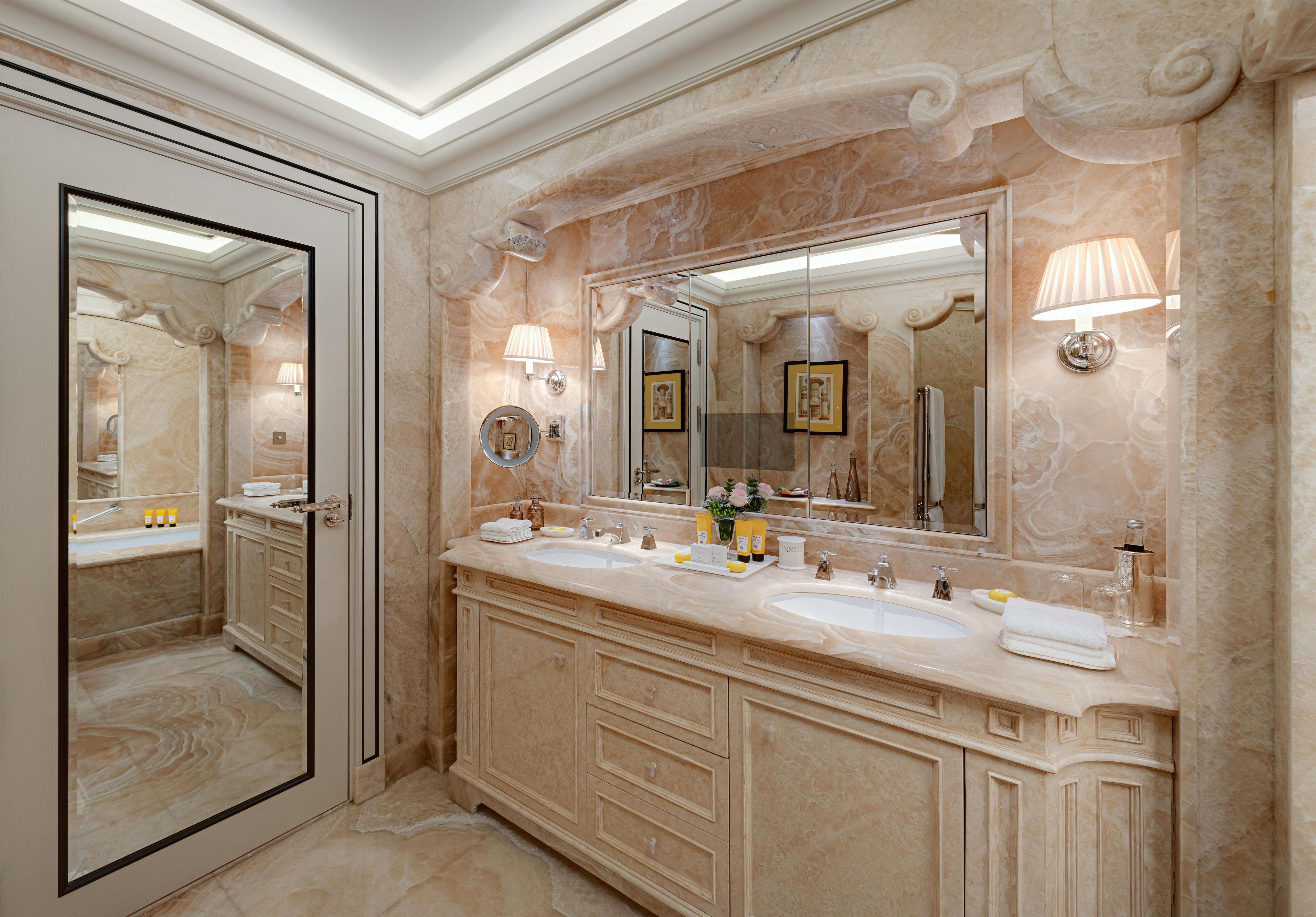 Un bagno lussuoso con un ampio specchio, due lavabi e un mobile contenitore con cassetti.