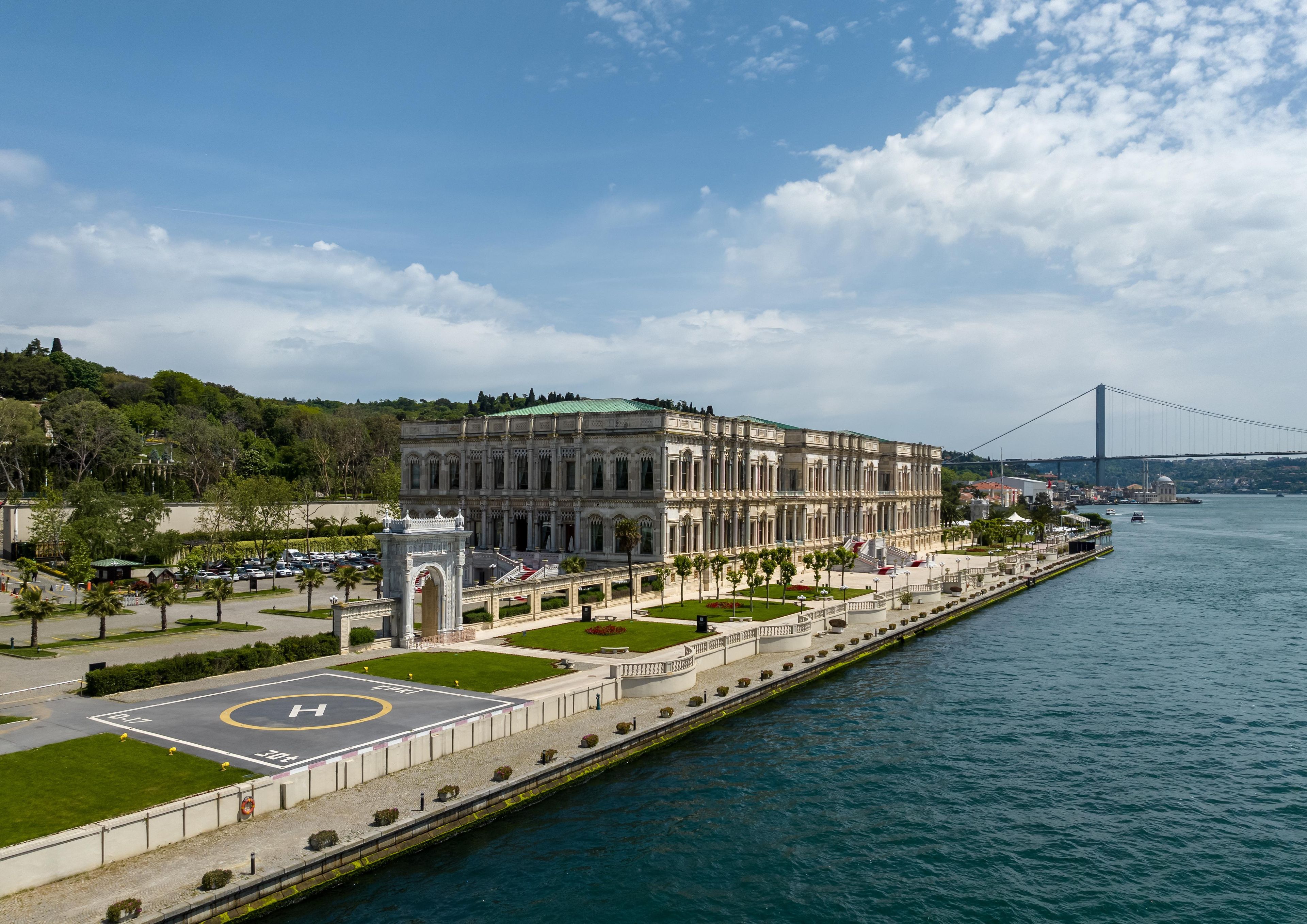 A waterfront building with a large parking area and a view of a bridge in the distance.