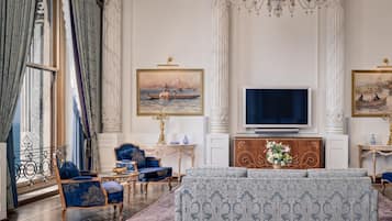 Ein luxuriöses Wohnzimmer mit einer großen Couch, passenden Sesseln, einem Fernseher und aufwendiger Dekoration.