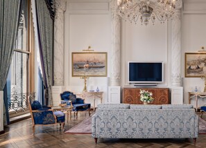 A luxurious living room with a large sofa, matching armchairs, a television, and ornate decor. - Ciragan Palace Kempinski (Istanbul)