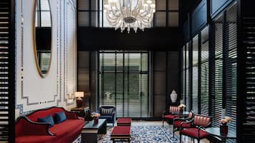 A modern interior with a red sofa, black chairs, a chandelier, and patterned walls.