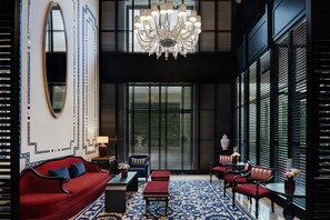 A modern interior with a red sofa, black chairs, a chandelier, and patterned walls. - Ciragan Palace Kempinski (Istanbul)