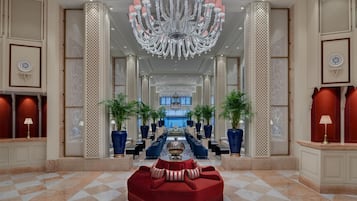 A spacious lobby with a grand chandelier, a red sofa, and a checkered floor.