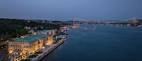 A waterfront hotel with a helipad, a large building with classical architecture, and a bridge in the background.
