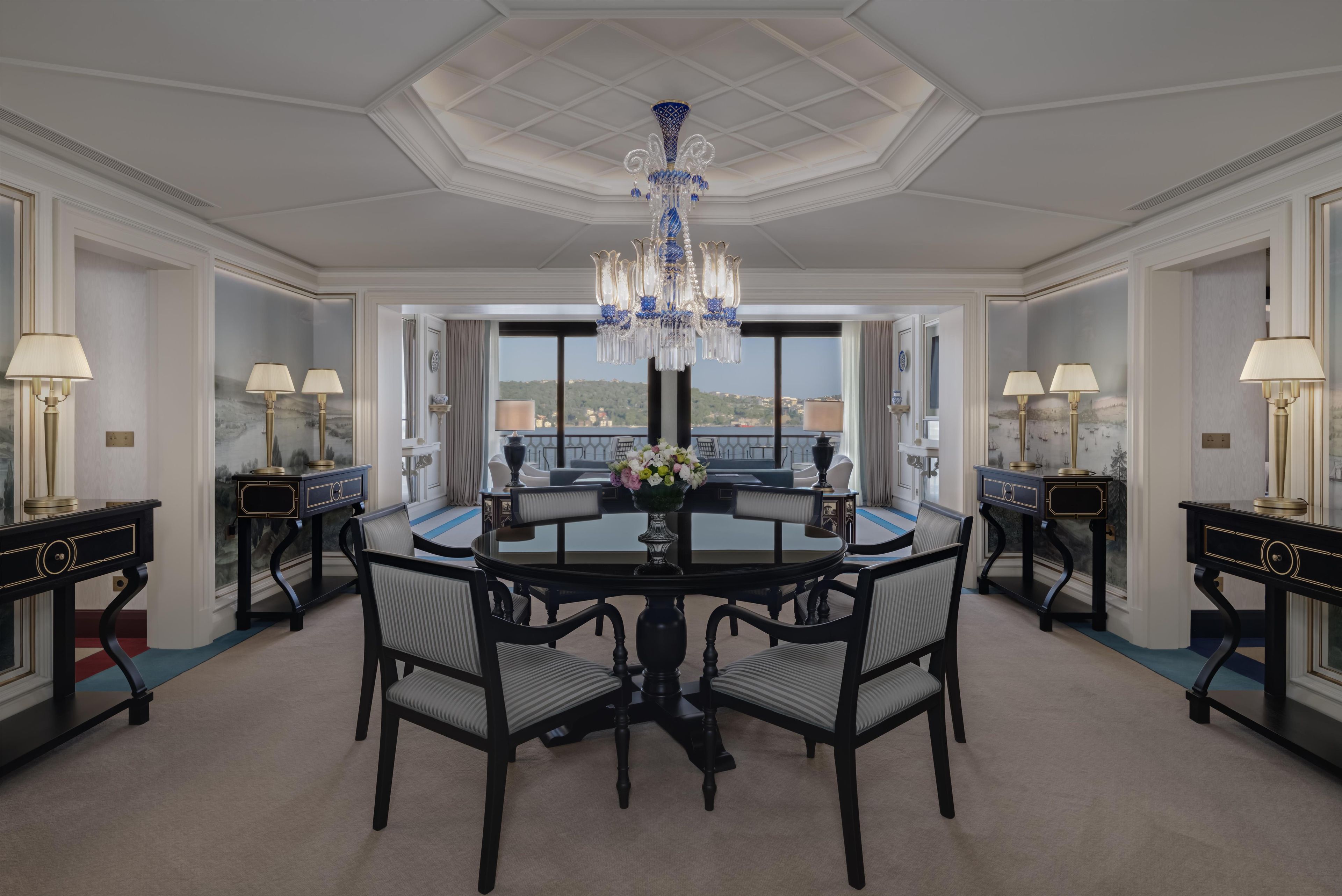 Une salle à manger élégante, avec une table ronde, des chaises et un lustre.