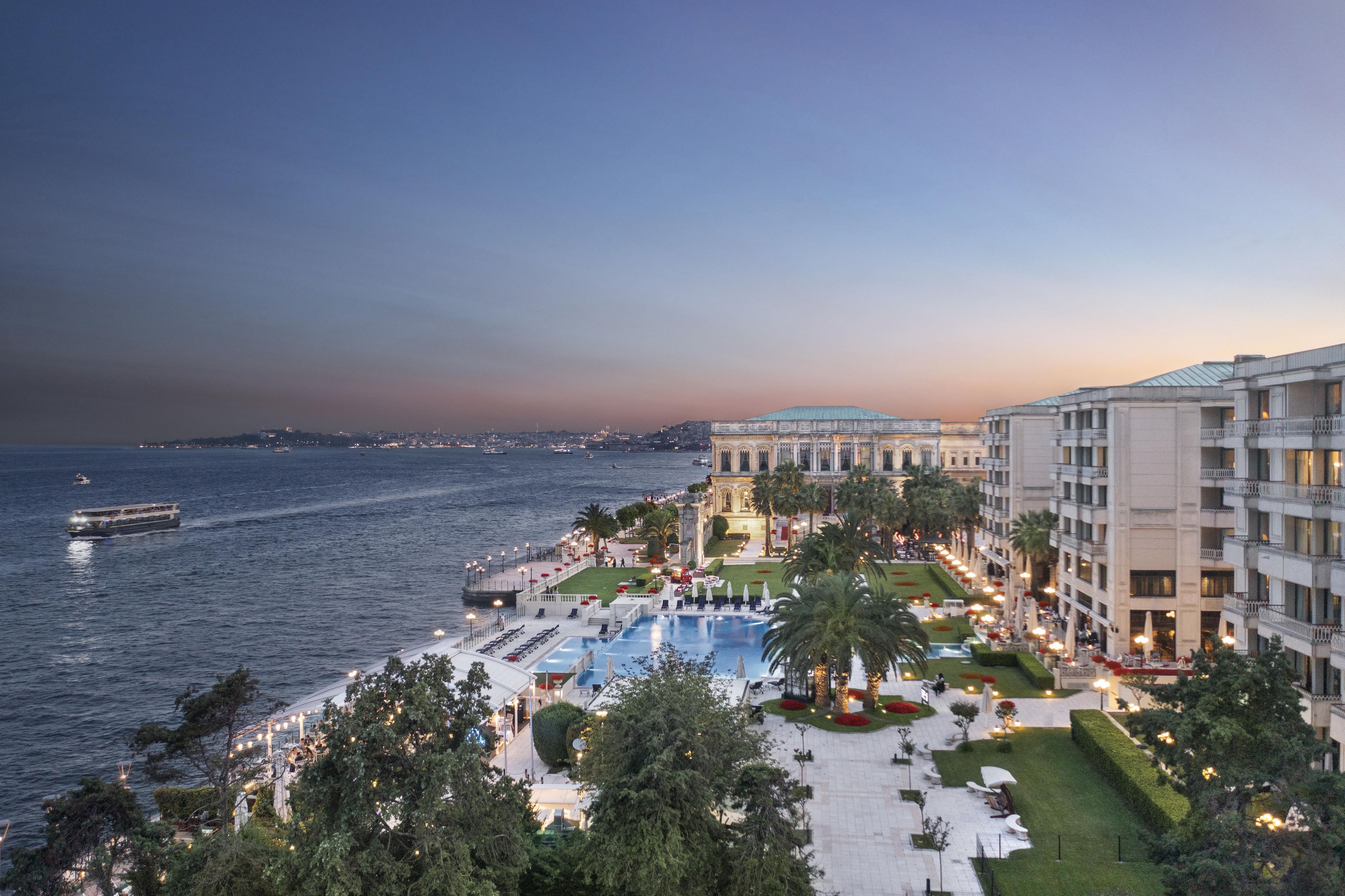 A resort with a pool, outdoor seating, and a view of the sea.