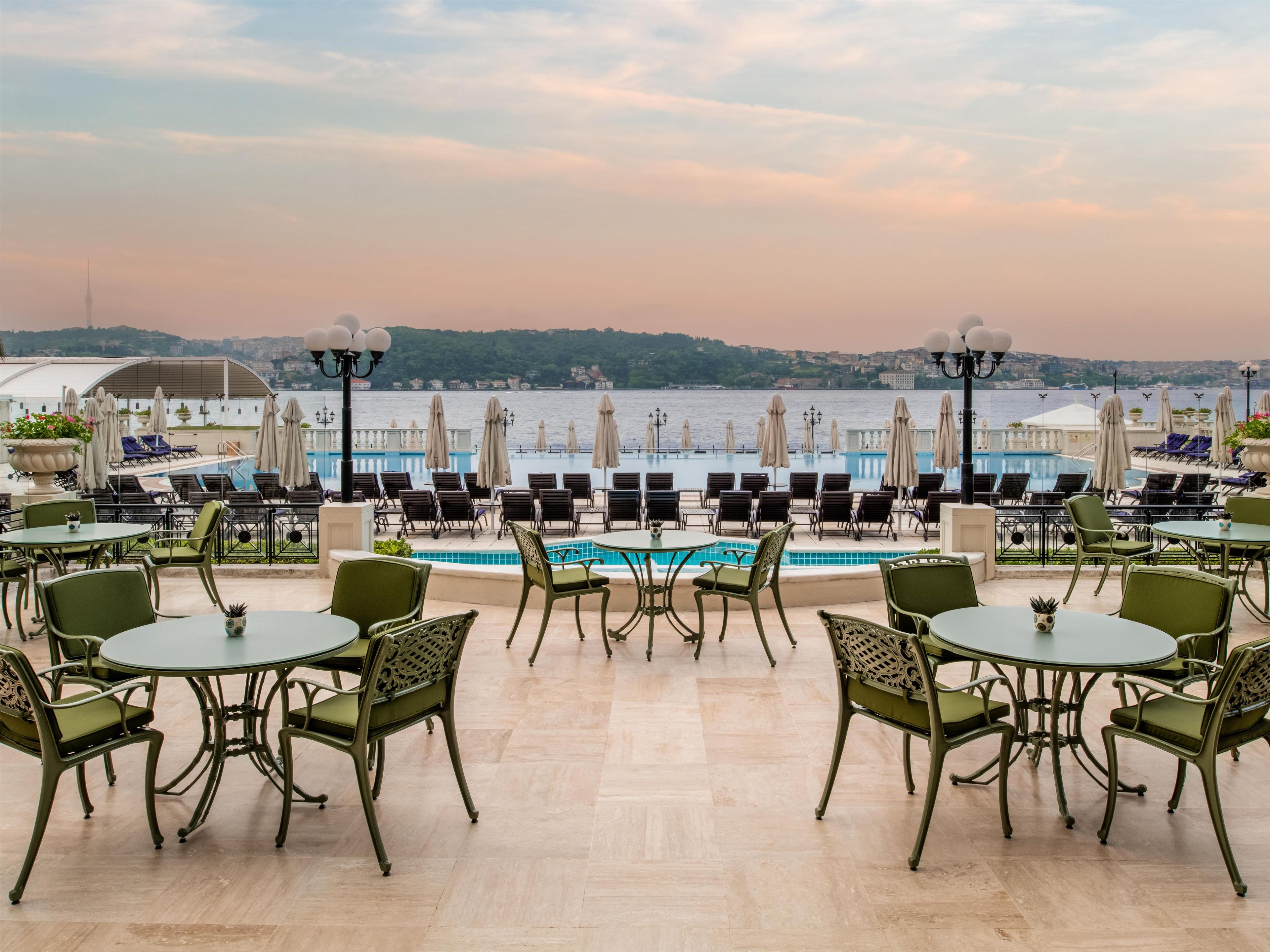 Terraço com área de estar externa e piscina com vista para um corpo de água.