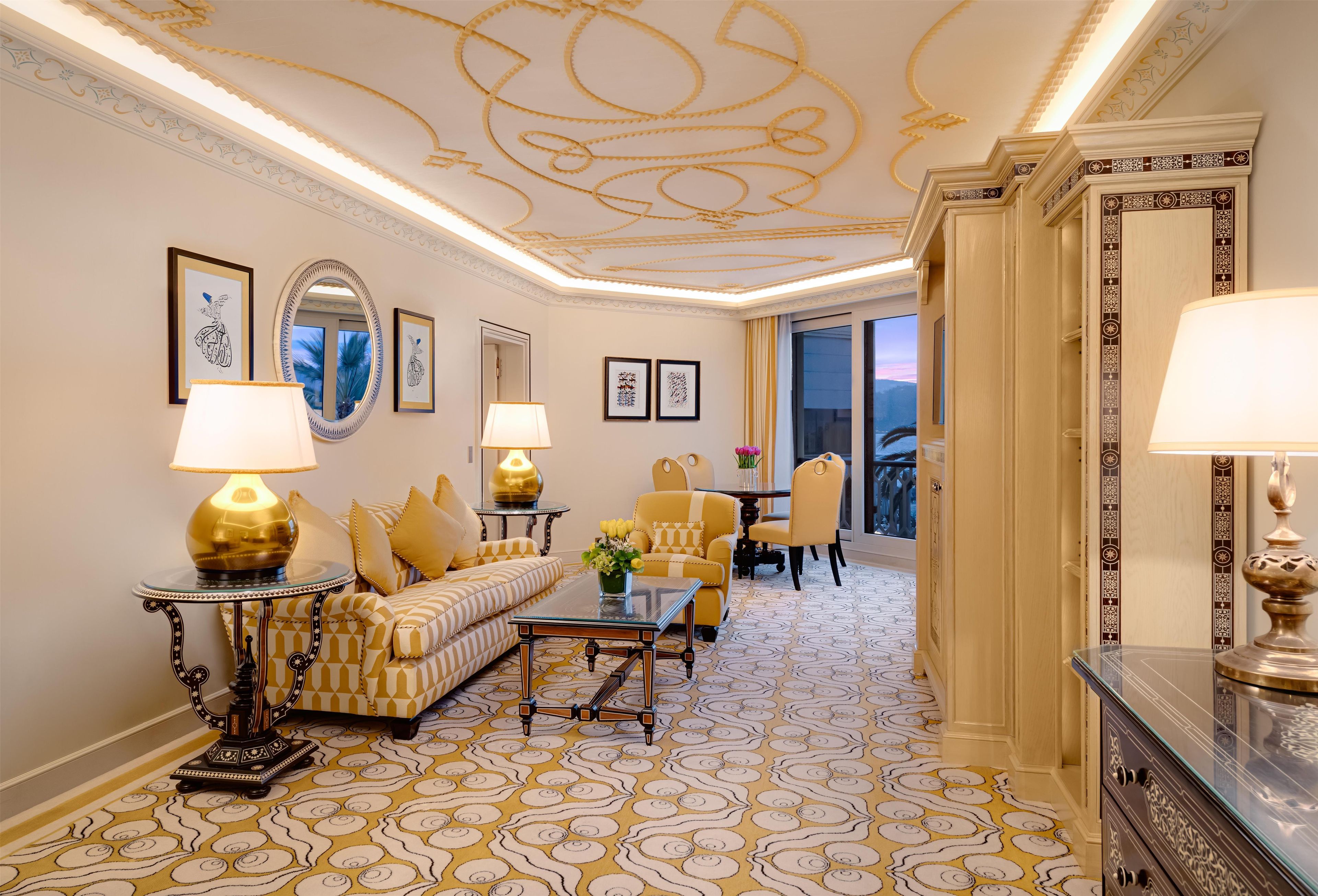 A luxurious room with a patterned carpet, elegant furniture, and decorative ceiling artwork.