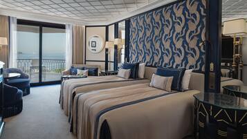 A hotel room with a large bed, a sitting area with a table, and a view of the sea.