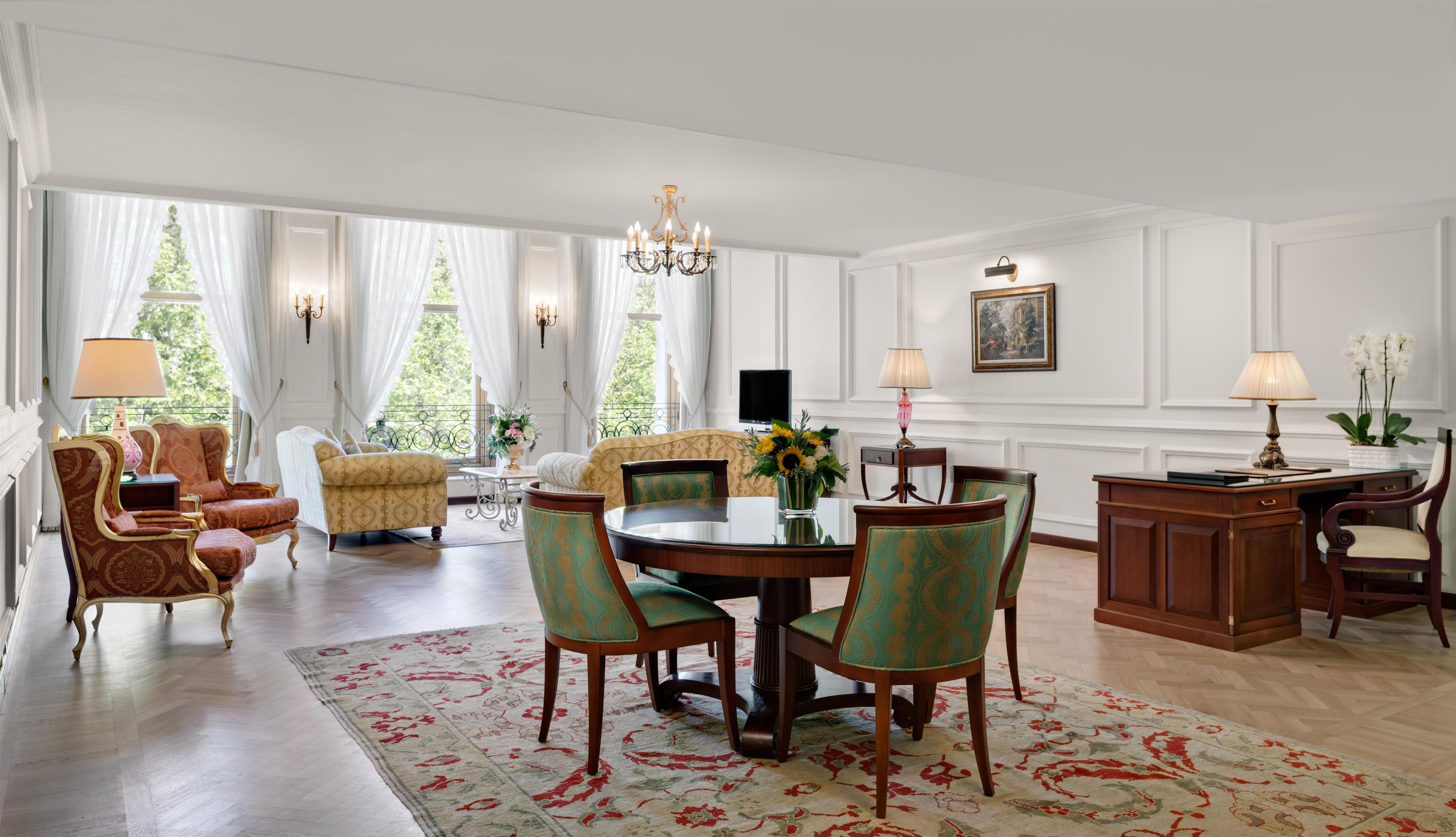 A spacious room with a dining area, a sofa set, and a chandelier.