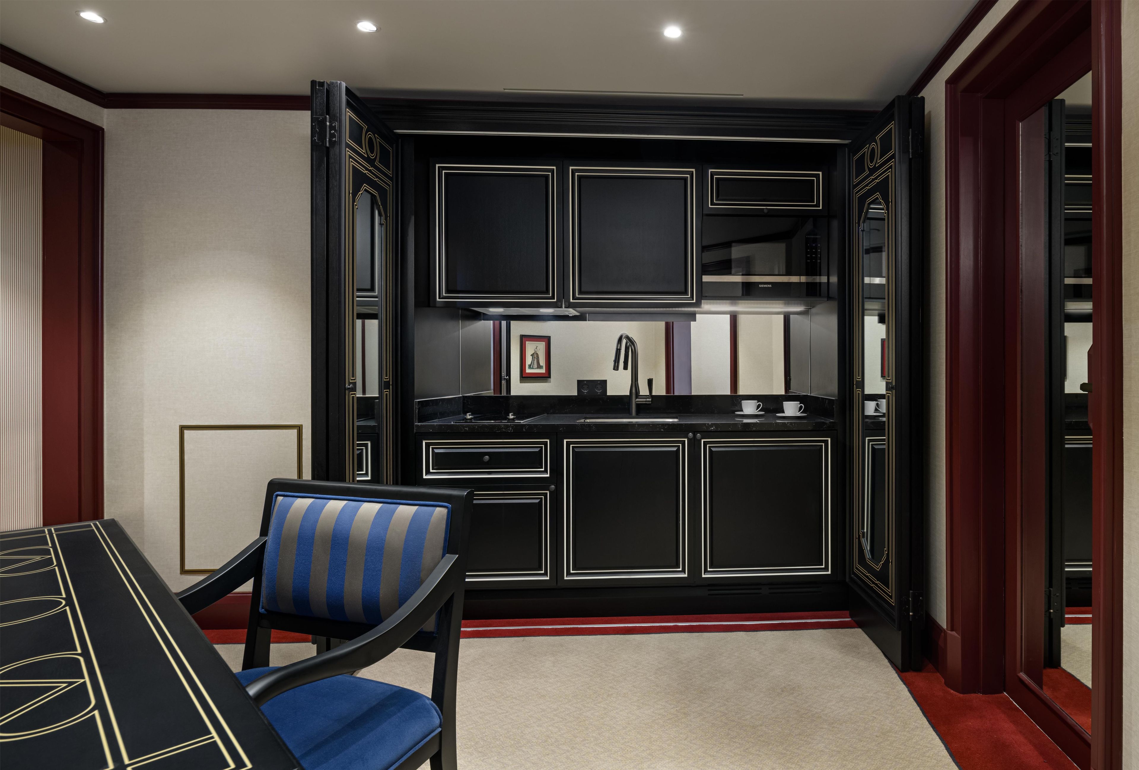 A modern kitchen with black cabinetry and a stainless steel countertop.