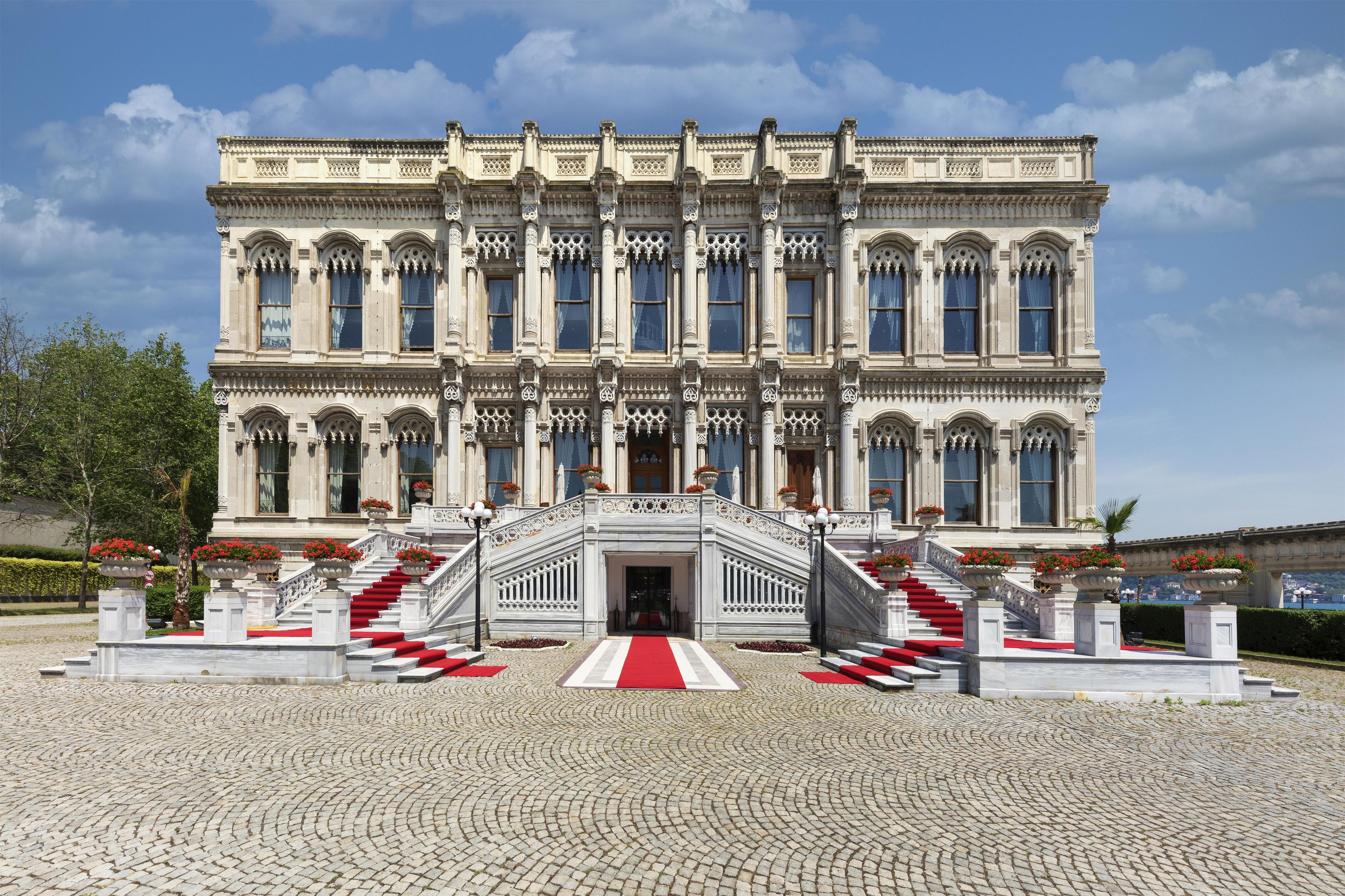 A grand building with a symmetrical facade, multiple windows, and a central entrance with a red carpet leading up to it.