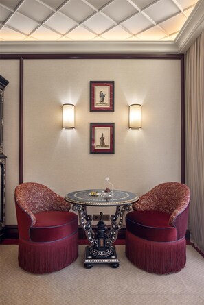 A room with a round table, two chairs, two wall-mounted lights, and two framed pictures. - Ciragan Palace Kempinski (Istanbul)