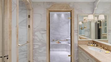 Un baño lujoso con paredes de mármol, un espejo grande y una bañera.