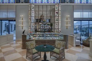 A lobby with a central display case, two wicker chairs, and a checkered floor. - Ciragan Palace Kempinski (Istanbul)
