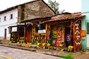 Un bâtiment aux couleurs vives, avec une enseigne indiquant la présence d’une auberge de jeunesse et d’un bar, une entrée bien visible et un mur de pierre orné de décorations colorées.