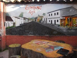 Une fresque représentant une scène de rue avec des bâtiments et une enseigne sur laquelle on peut lire : « Exportamos Alegre ».