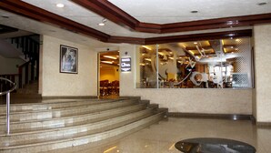A hotel lobby with a staircase leading to a second floor, a reception desk, and a seating area. - Hotel Parque Satelite (Tlalnepantla de Baz)