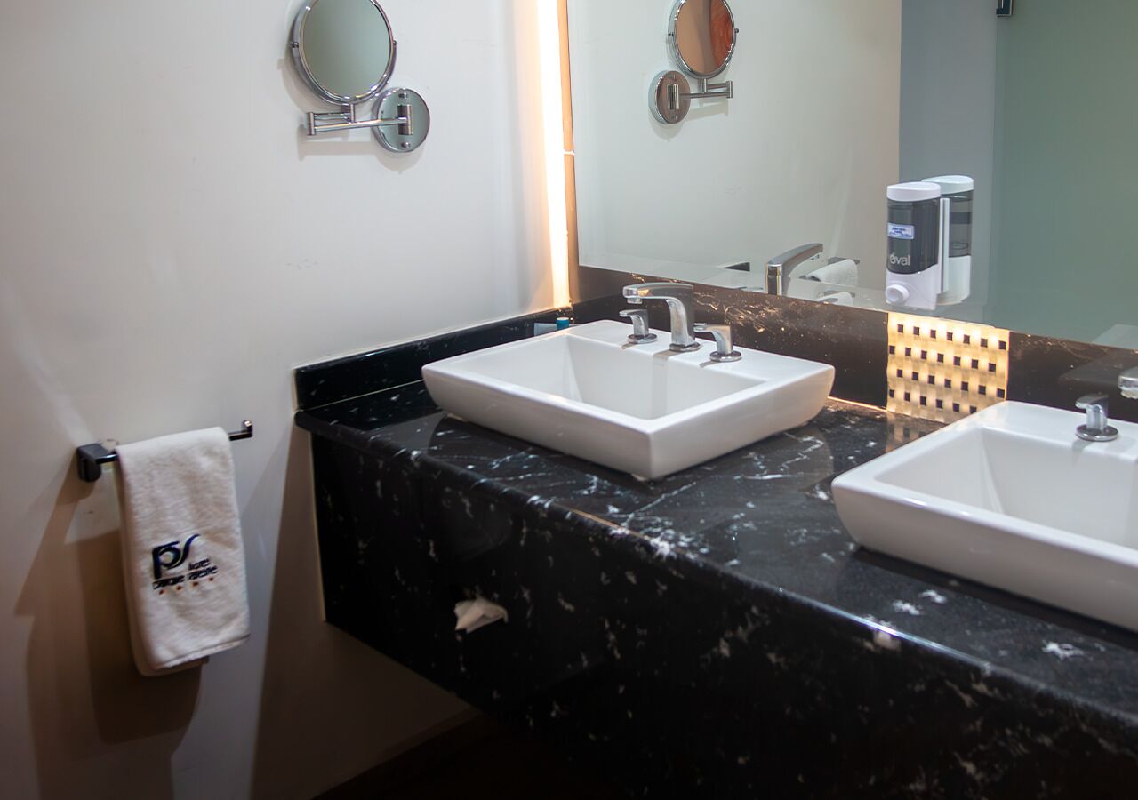 Une salle de bain avec deux lavabos blancs, un porte-serviettes avec une serviette et un miroir.