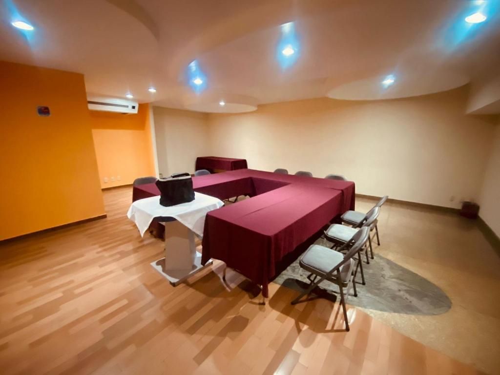 Un salón de conferencias con una larga mesa y sillas, un atril y piso alfombrado.