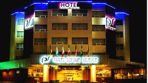 A hotel with a prominent "HOTEL" sign, multiple flags, and a well-lit entrance. - Hotel Parque Satelite (Tlalnepantla de Baz)