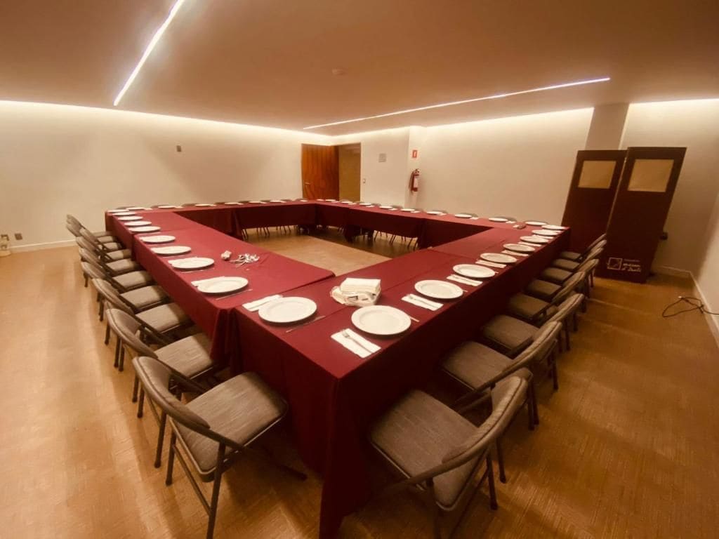 Un salón de conferencias con una larga mesa, sillas y un extintor.