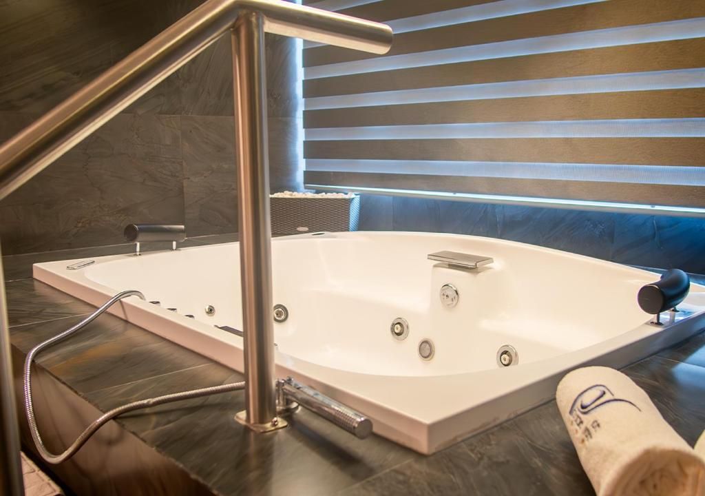 A modern bathroom with a large bathtub, a showerhead, and a towel.